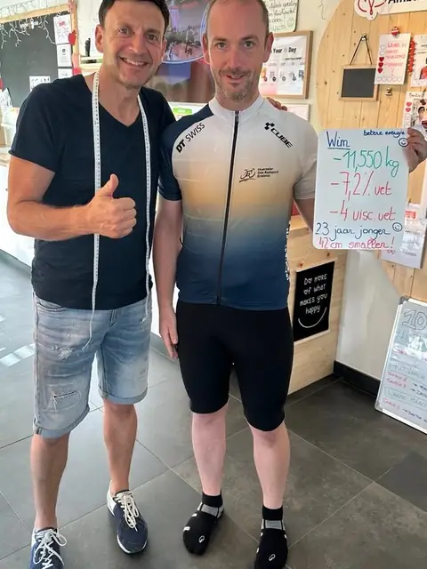 Een coach van de club poseert met een lid en het bordje met zijn resultaten