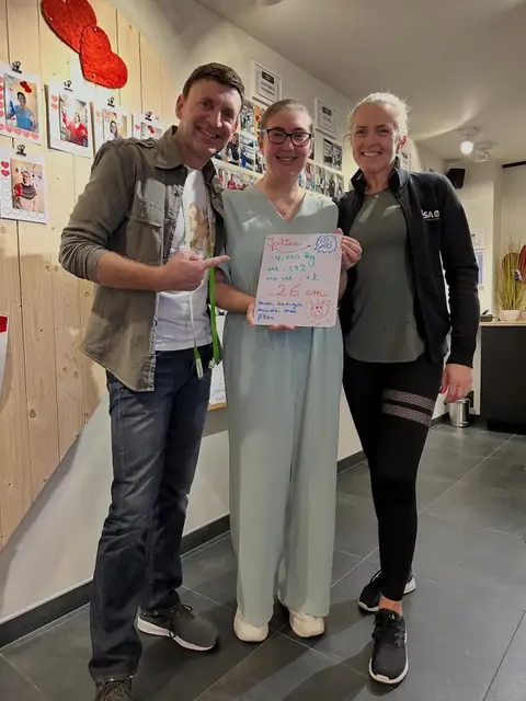 Een coach van de club poseert met een lid en het bordje met zijn resultaten